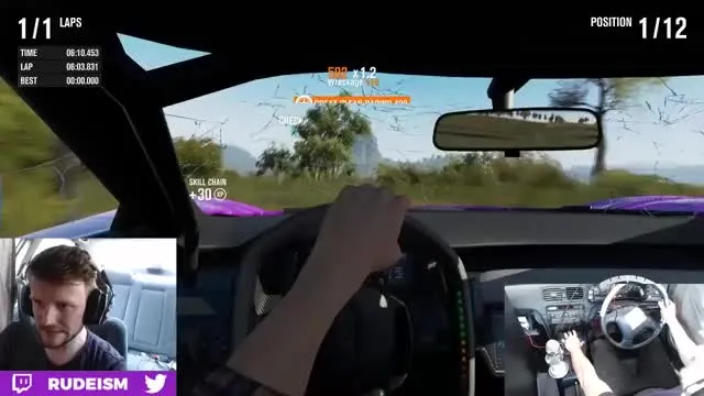 Beck playing a driving game using the dashboard of an actual car